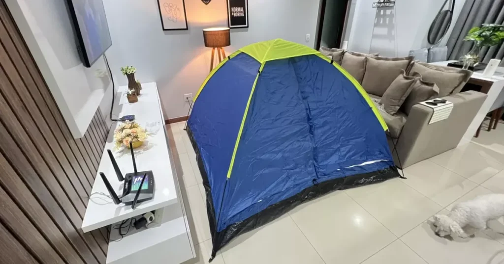Barraca de camping azul e verde montada dentro de uma sala de estar moderna